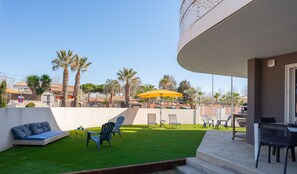 A balcony with a green lawn, outdoor furniture, and a yellow umbrella.