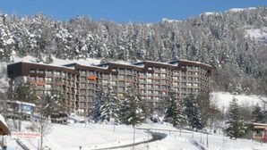 Un hôtel à plusieurs étages avec une piste de ski en arrière-plan.