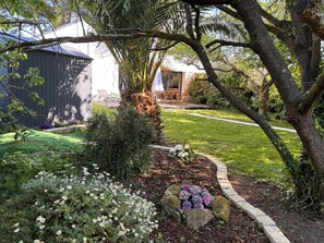 A well-maintained garden with a lawn, a variety of flowers, and a stone pathway. - Nice quiet house, only a few yards away from the Rospico beach (Finistère)