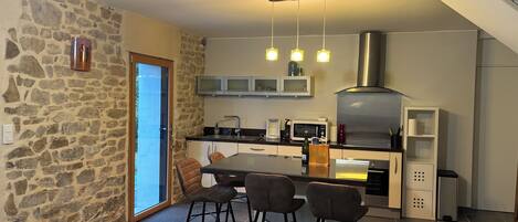 A modern kitchen with a stone wall, a dining area with bar stools, and a staircase.