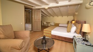 Un dormitorio acogedor con cama, mesita de noche, lámpara y una pequeña mesa redonda con hervidor.