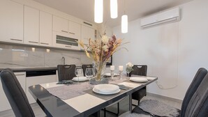 A modern kitchen with white cabinets, a marble countertop, and a dining area with a black table, grey chairs, and a vase with dried flowers. - Villa Jenny, private pool, 4+1, peace and quiet, BBQ (Murvica)