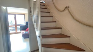 Una escalera de madera con paredes blancas que conduce a una habitación con un sofá y una ventana.