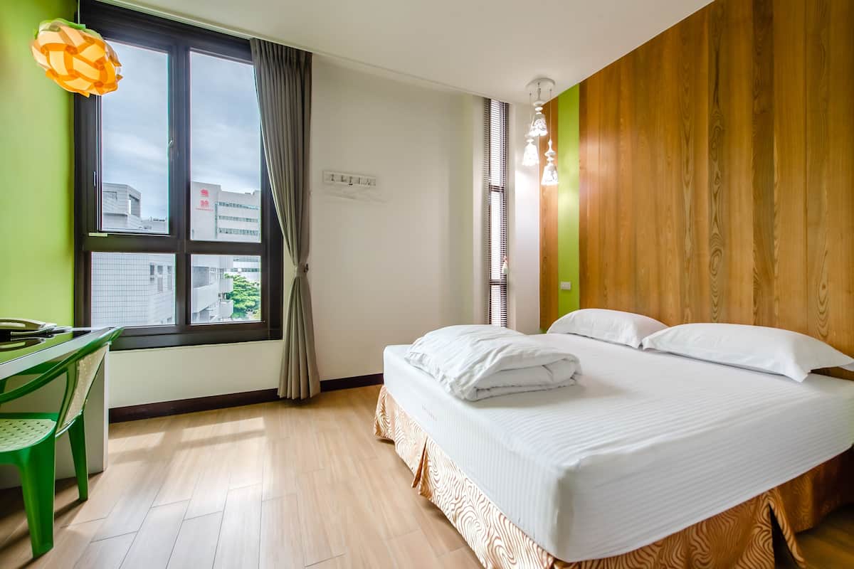 Una habitación de hotel con cama, escritorio y ventana con cortinas.
