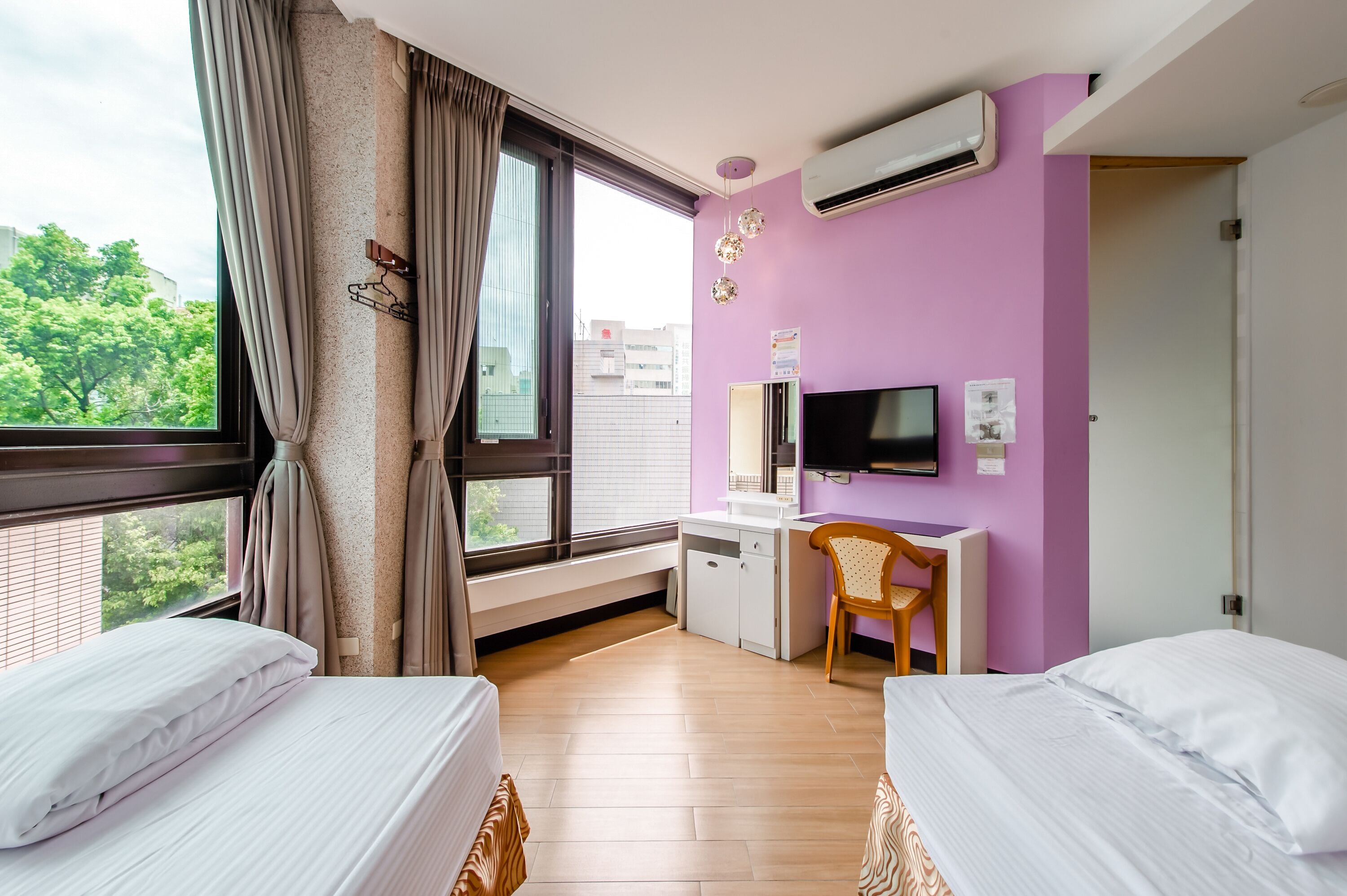 Una habitación de hotel con dos camas, un escritorio, una silla, un televisor y un equipo de aire acondicionado.