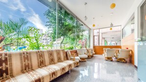 A modern lobby with a sofa, chairs, and tables, large windows with plants, and a clean, polished floor. - Lightness Hotel (Tainan)