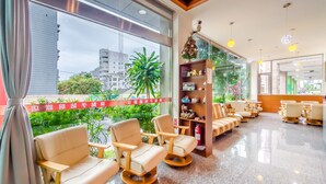 A modern hotel lobby with a seating area, a reception desk, and a large window offering a city view. - Lightness Hotel (Tainan)