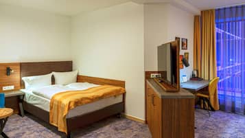 Een hotelkamer met een bed, een bureau, een stoel, een televisie en een raam met gordijnen.
