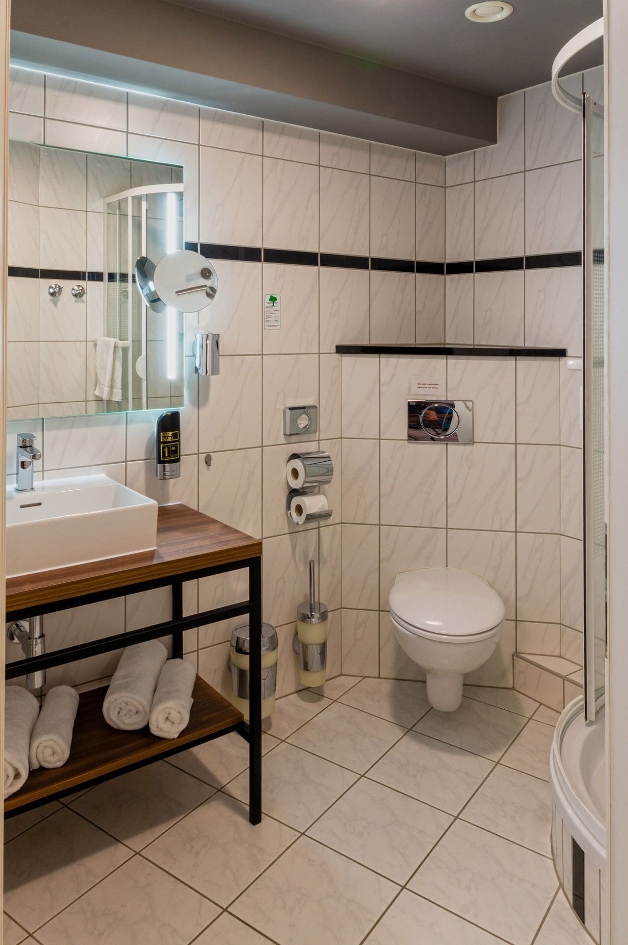 Un baño moderno con lavamanos, espejo, inodoro y zona de ducha.