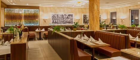 Un restaurante moderno con barra central, cabinas y un techo alto con iluminación empotrada.