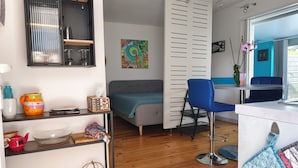 Un espai habitable reduït amb petita cuina, sofà, zona de menjador i finestra amb vista.