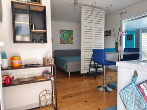 A compact living space with a kitchenette, a sofa, a dining area, and a window with a view.