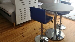 Habitació moderna amb un llit, una taula de dinar i dues cadires, i una porta corredissa.
