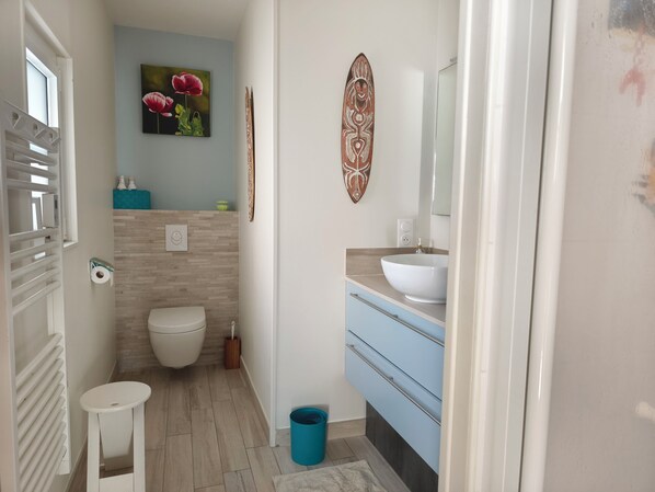 A modern bathroom with a toilet, sink, and a small stool.
