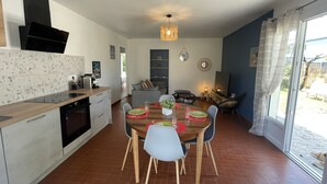 A modern kitchen with a dining area, featuring a wooden table, chairs, and a chandelier. - 600m Plage (Saint-Palais-sur-Mer)