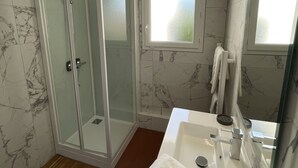 A modern bathroom with a glass-enclosed shower, a large mirror, and a marble-tiled wall. - 600m Plage (Saint-Palais-sur-Mer)