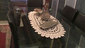 A dining table with a lace table runner, a vase with flowers, and a framed picture on the wall. - luxury apartment in the center of gueliz, near carre eden mall (Marrakesh)