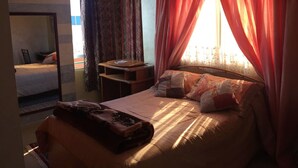 A bedroom with a bed, a bedside table, a chair, and a window with curtains. - luxury apartment in the center of gueliz, near carre eden mall (Marrakesh)