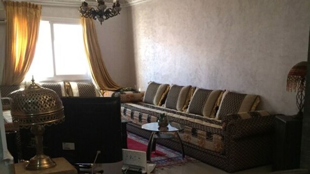 A living room with a sofa, a television, and a decorative lamp. - luxury apartment in the center of gueliz, near carre eden mall (Marrakesh)