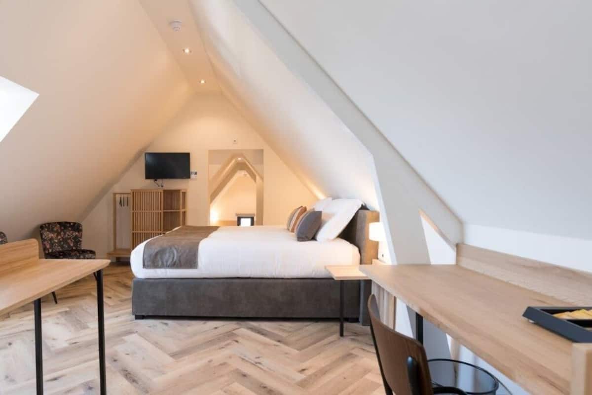 A bedroom with a bed, a desk, a chair, a TV, and a wardrobe.
