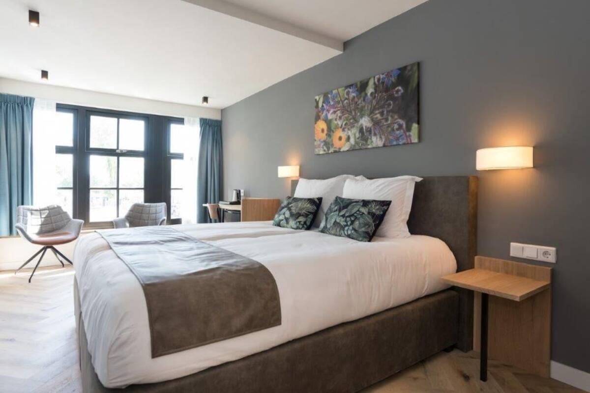 A modern hotel room with a large bed, two bedside tables, a desk, and a chair.