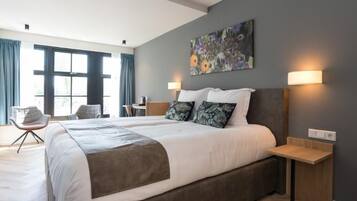 A modern hotel room with a large bed, two bedside tables, a desk, and a chair.