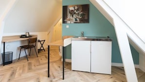 Una cocina compacta con una mesa de comedor de madera, un refrigerador blanco y una pared de acento color verde azulado.