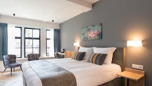 Una habitación de hotel moderna con una cama grande, dos mesitas de noche, un escritorio y una silla.
