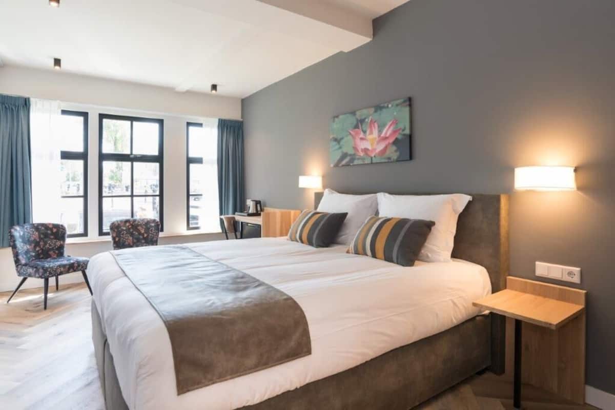 A modern hotel room with a large bed, two bedside tables, a desk, and a chair.