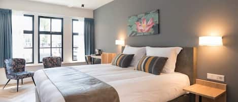 A modern hotel room with a large bed, two bedside tables, a desk, and a chair.