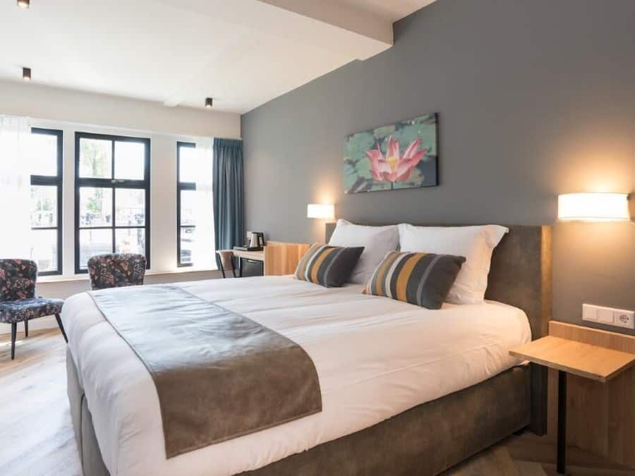 Una habitación de hotel moderna con una cama grande, dos mesitas de noche, un escritorio y una silla.