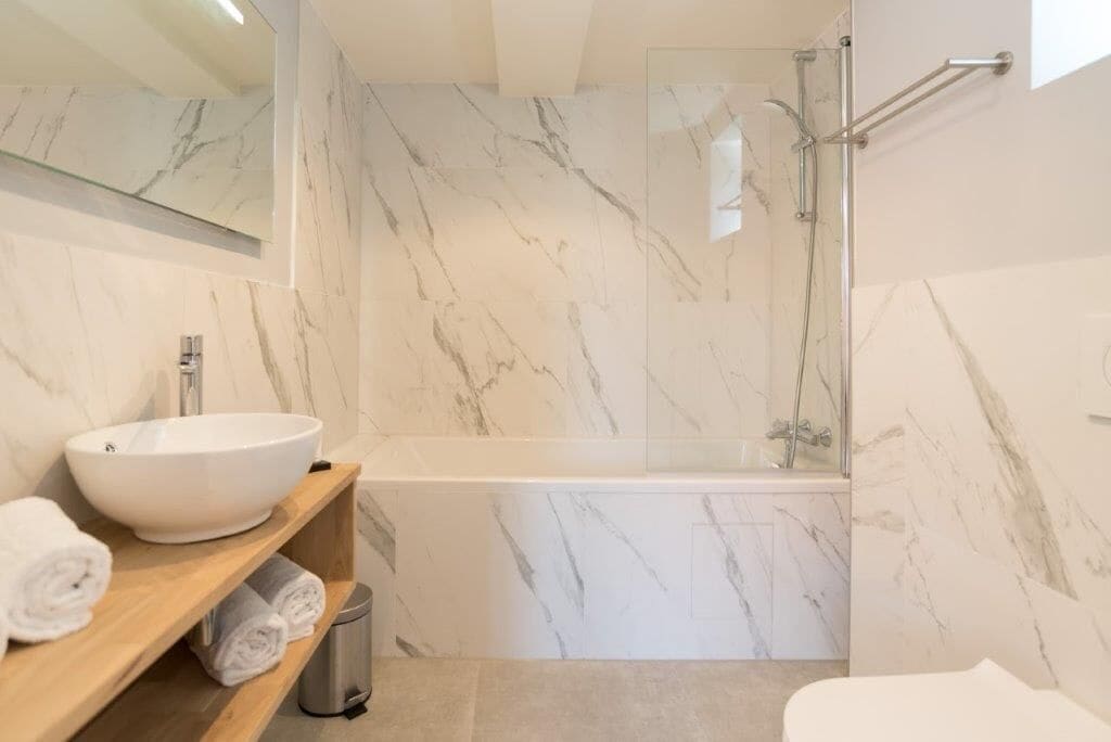 Een moderne badkamer met een groot wit wastafelmeubel, een badkuip en een douchecabine met glazen wanden.