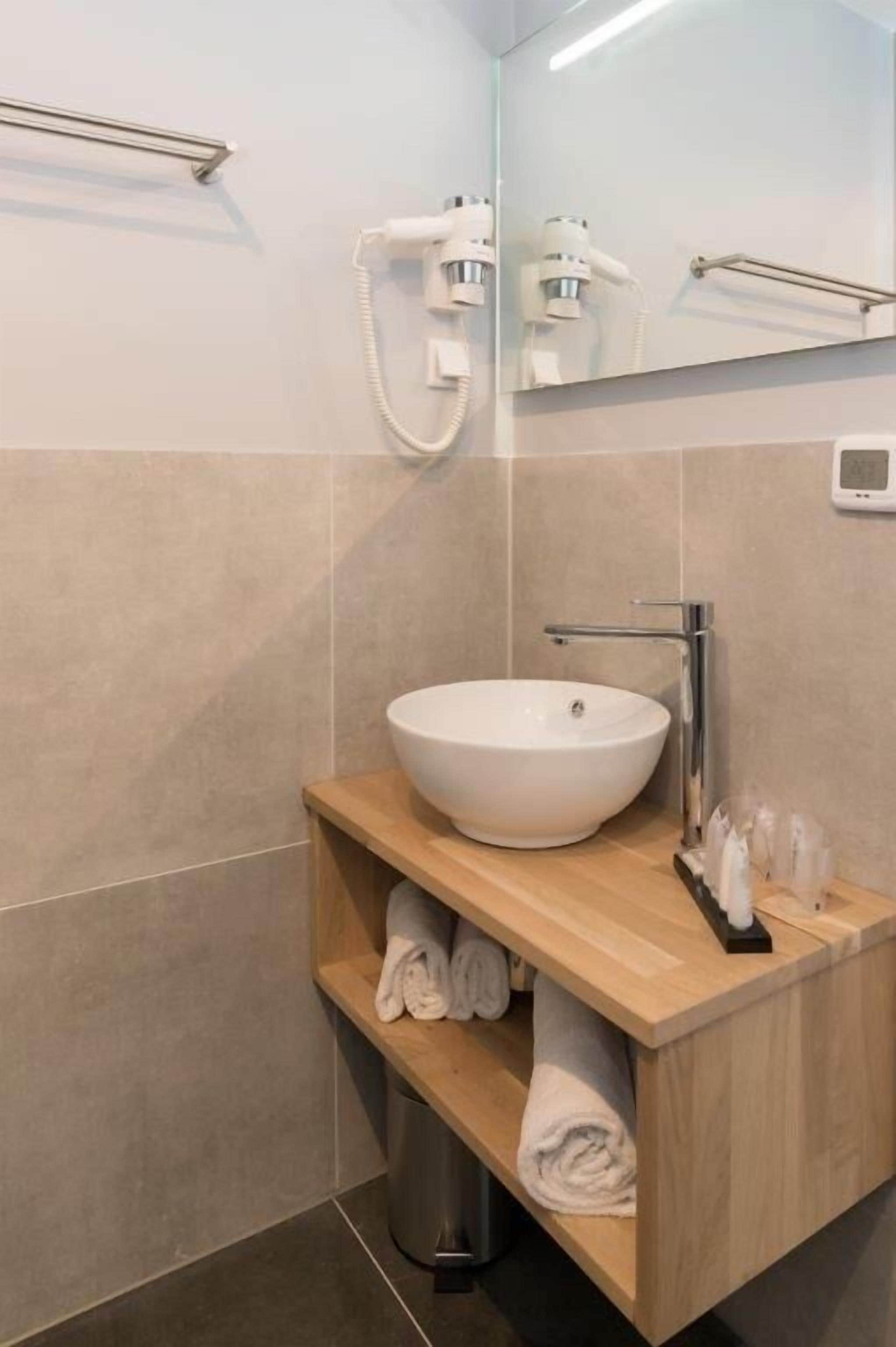 A modern bathroom with a white vessel sink, wooden vanity, and a towel rack.