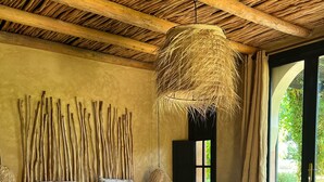 Une chambre avec un lit en bois, un plafond en osier et une vue sur la verdure environnante.
