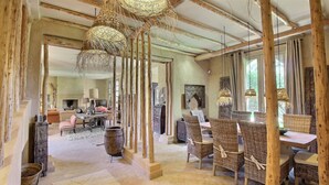 Un intérieur rustique avec des poutres apparentes, des meubles en osier et des luminaires suspendus en fibres tressées.