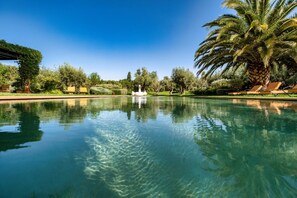 A clear pool with a swan statue in the center, surrounded by palm trees and greenery. - Marrakech Route des Golfs SPLENDID BELDI CHIC property for rent (Marrakech)