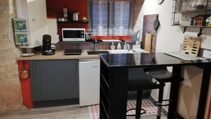 Eine kompakte Küche mit Mikrowelle, Kaffeemaschine und kleinem Kühlschrank.