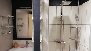 Ein modernes Badezimmer mit einer Duschkabine aus Glas, einem weißen Waschbecken und einem Holzschrank.