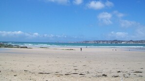 A beach with a clear sky, rocky coastline, and a few people walking. - House 6 pers beach 3km town center 5mn walk (Crozon)