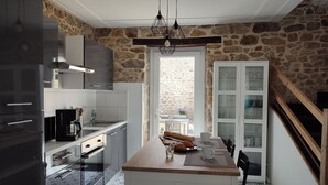A kitchen with stone walls, a wooden island, and a view to the outside. - House 6 pers beach 3km town center 5mn walk (Crozon)