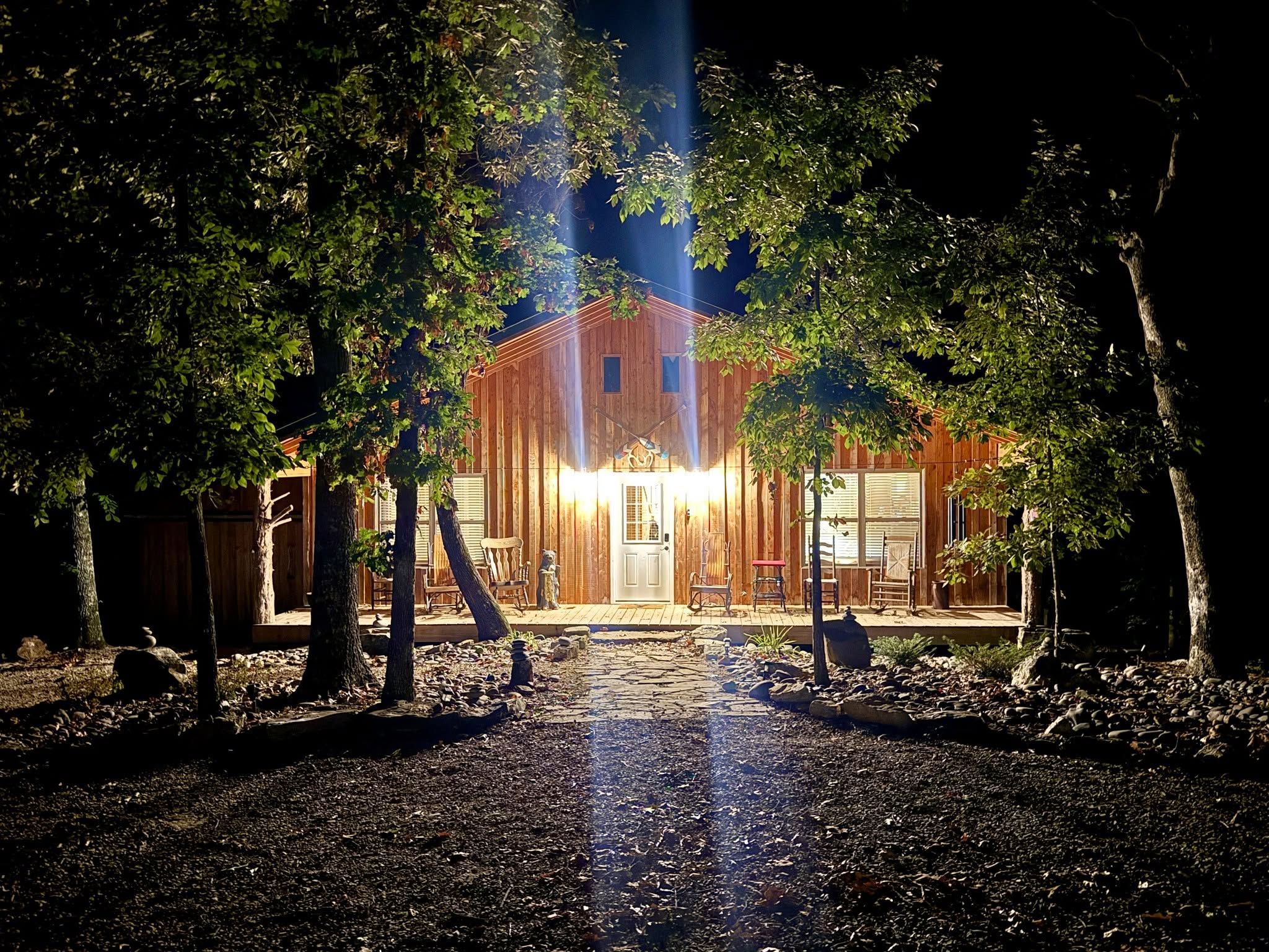 A wooden building with a front porch, surrounded by trees, and a pathway leading to the entrance.