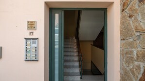 A building entrance with a stone wall, a staircase, and a mailbox with room numbers.