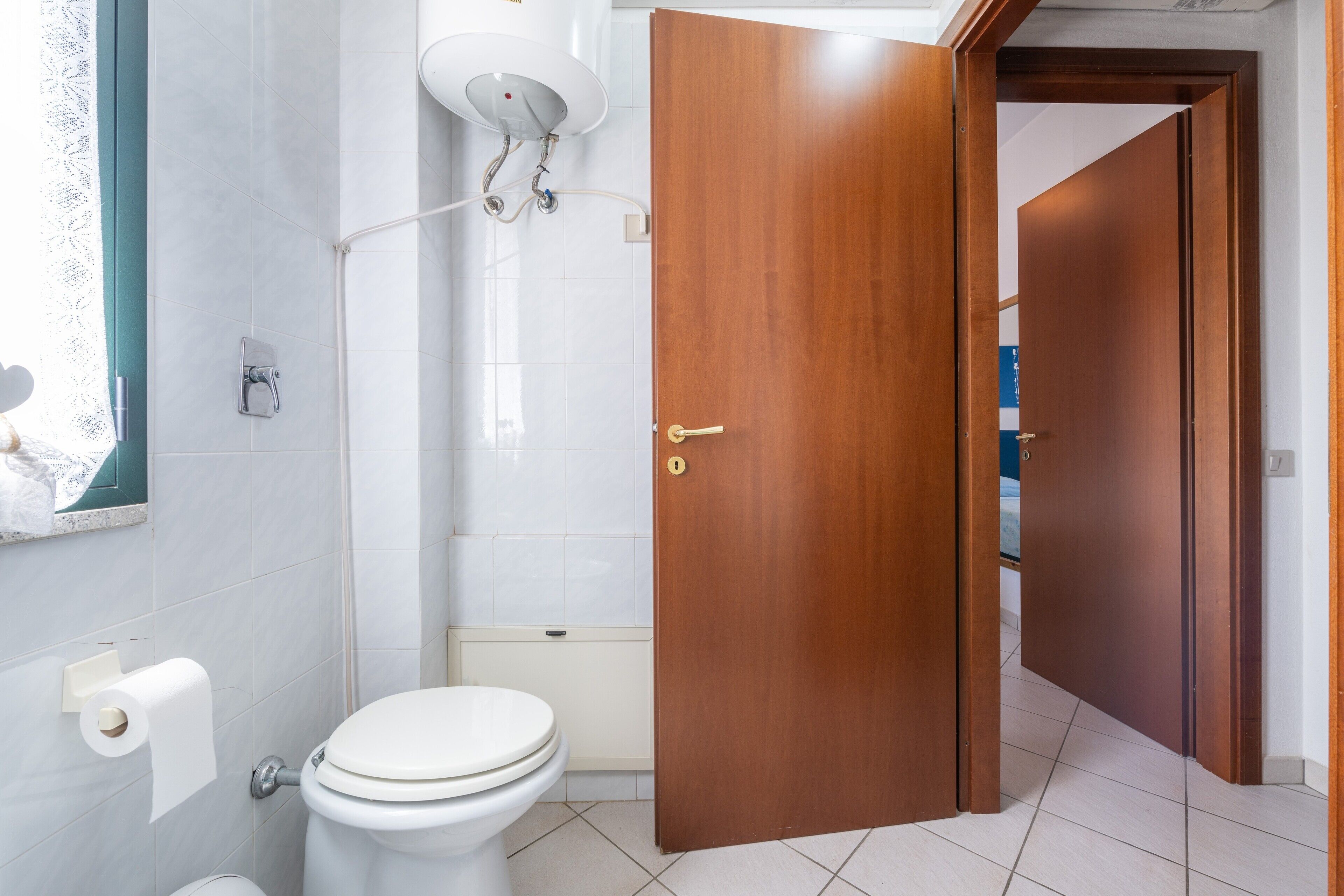 Een badkamer met toilet, douche en een houten deur.