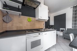 Una cocina moderna con estufa a gas, armarios blancos y encimera gris.