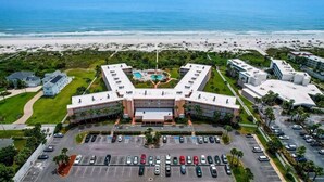 A hotel with a central courtyard, multiple parking lots, and a beach view.