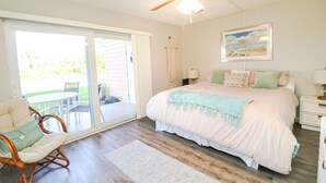 A bedroom with a bed, a ceiling fan, a window, and a door leading to a balcony.