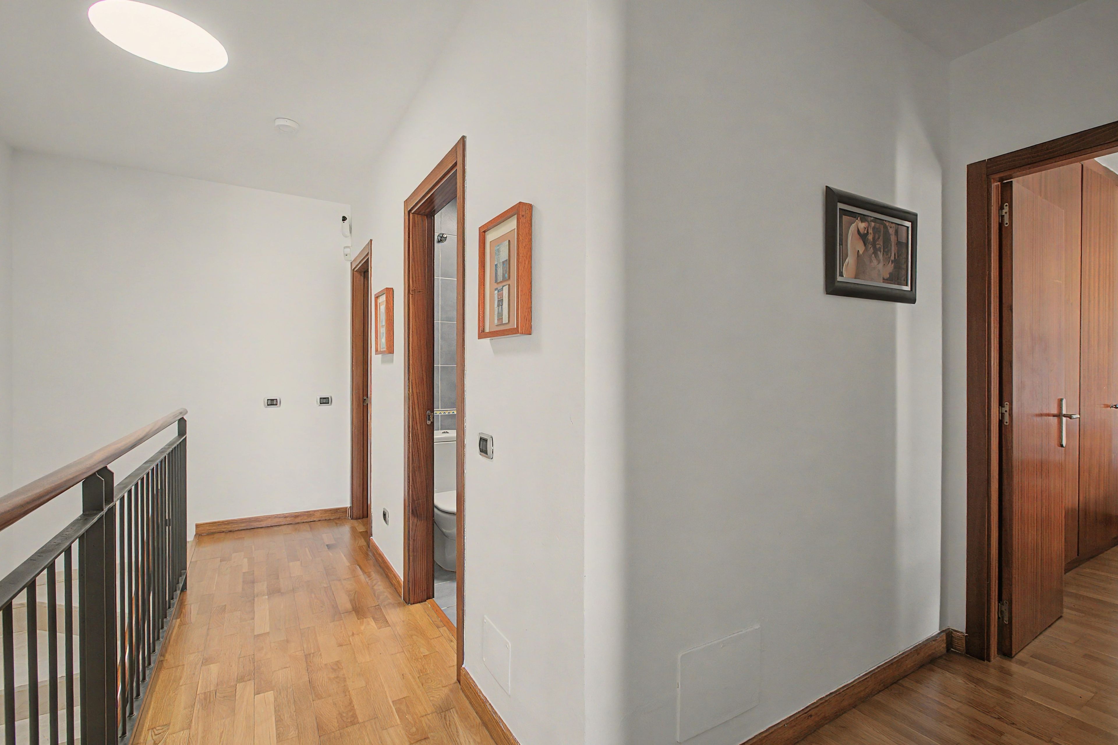 A hallway with wooden flooring, white walls, and a wooden door at the end.