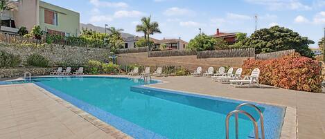 A swimming pool with lounge chairs and a stone wall.