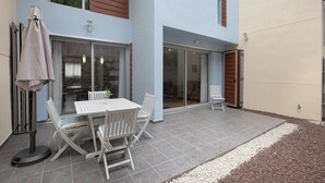 An outdoor patio with a table and chairs, a patio umbrella, and a sliding glass door leading to a covered area. - Vacation Home 'La Quinta Adosado' with Sea View, Shared Pool & Wi-Fi (Santa Ursula)