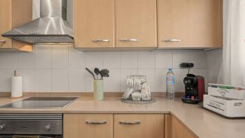 A modern kitchen with wooden cabinets, a stainless steel range hood, a water dispenser, and a coffee maker.